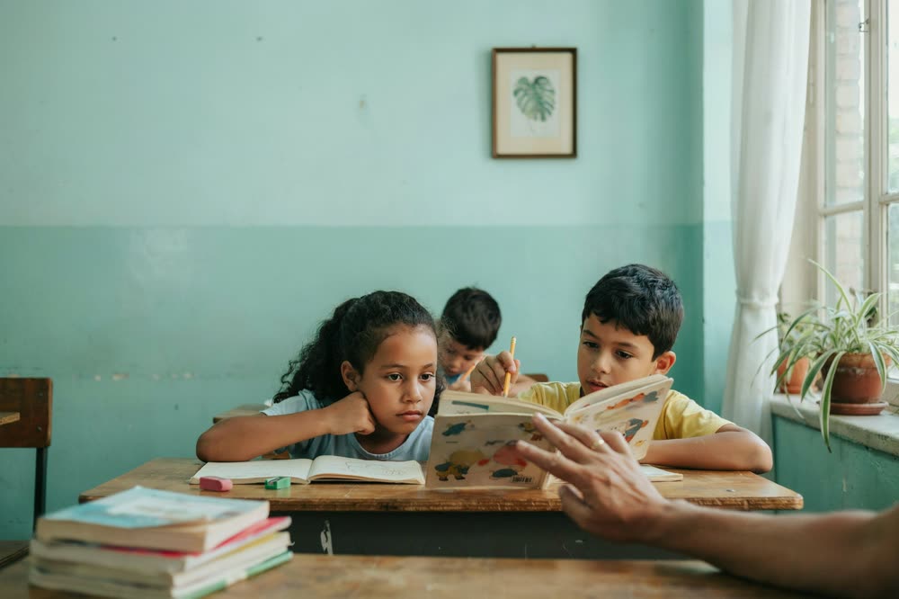 Crianças lendo um livro junto com a professora
